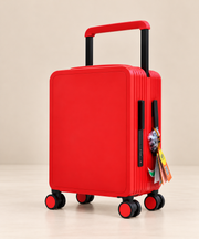 A bright red hard-shell carry-on suitcase with a telescoping handle extended and four spinner wheels, shown on a clean beige studio background. A small colorful tag hangs from the side handle.