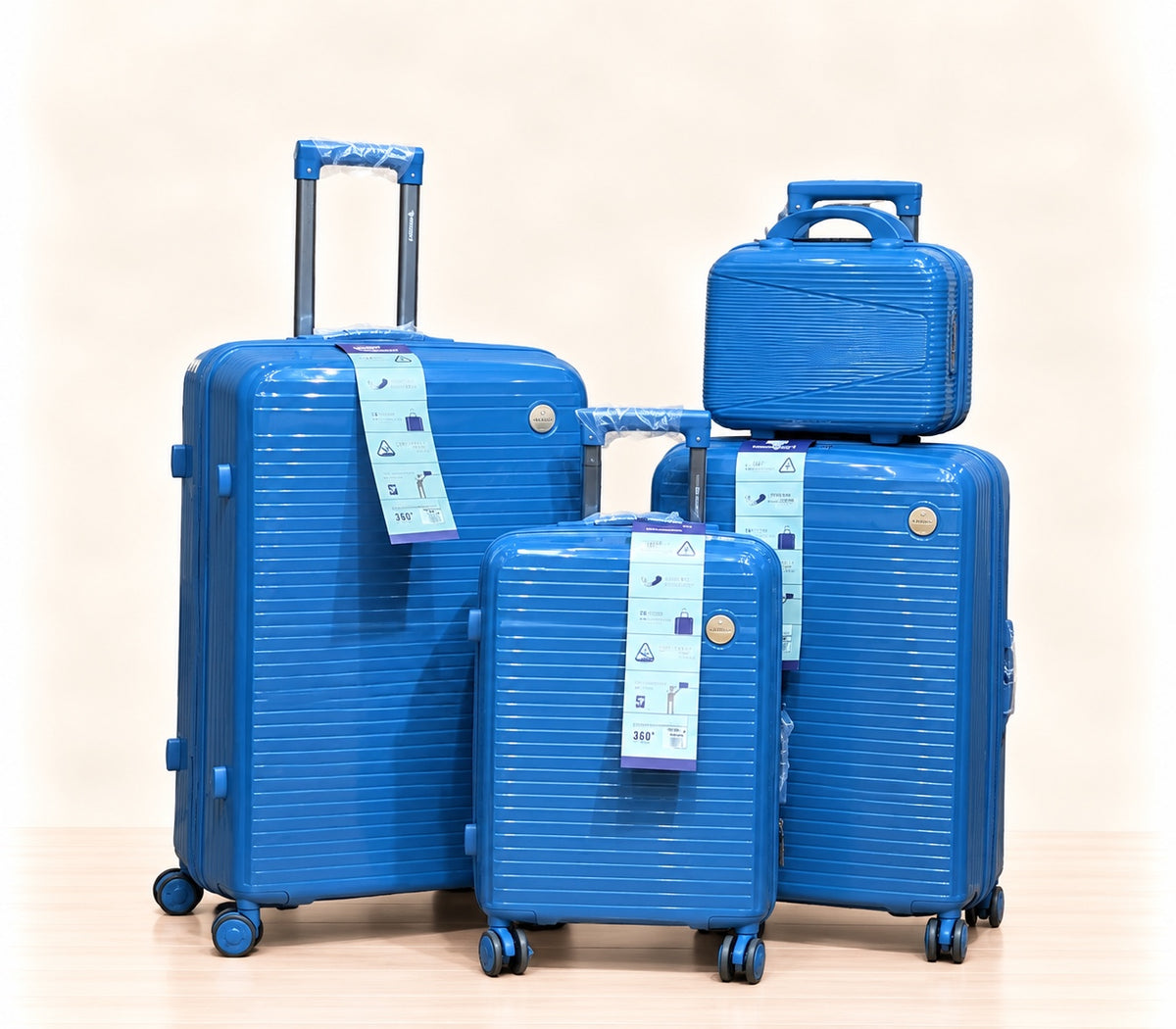 A three-piece pink luggage set consisting of a large spinner suitcase, a medium spinner suitcase, and a matching small handbag, all with telescoping handles and wheels, shown on a light beige background. 