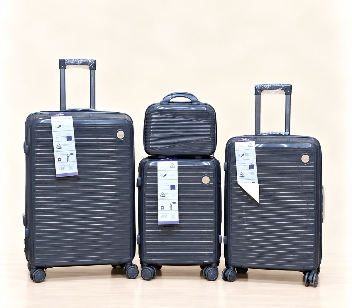 A three-piece pink luggage set consisting of a large spinner suitcase, a medium spinner suitcase, and a matching small handbag, all with telescoping handles and wheels, shown on a light beige background. 